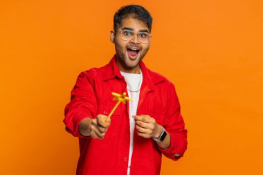 Sihirbaz Arap sihirbaz sihirli değnek ve sihirli değnekle hareket ederek dilekleri gerçekleştiriyor. Sihirbaz reklam indirimi yapıyor. Turuncu arka planda izole Hintli sakallı adam.