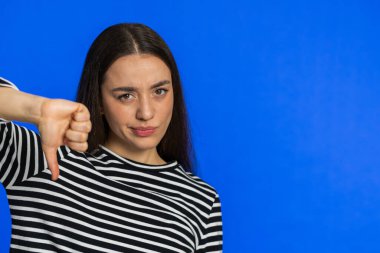Hoşlanmamak. Mutsuz bir kadın, hoşnutsuzluğunu, memnuniyetsizliğini ve olumsuz tepkilerini dışa vuruyor. İçerideki güzel kız mavi arka planda izole edilmiş. Kopyalama alanı