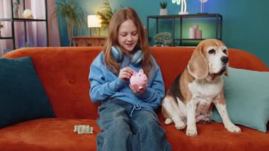 Genç kız gelecek eğitim için kumbaraya bir dolar cep harçlığı koyuyor. Bozuk para kutusu olan mutlu kadın gelir artışını finanse ediyor, ekonomi evde kanepede av köpeğinin yanında oturuyor..