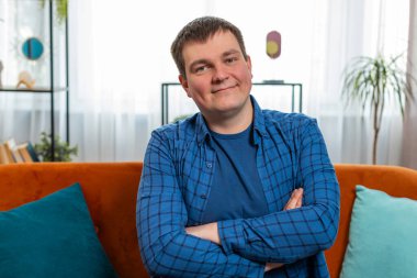 Mutlu beyaz adamın portresi kanepeye oturup kameraya bakıyor ve evde gülümsüyor. Yakışıklı, çekici görünümlü, kaygısız hayattan zevk alan bir adam. Oturma odasında dinleniyor.