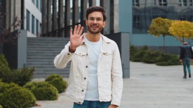 Hoş geldiniz. Hintli adam kameraya dostça gülümsüyor, el sallıyor selam veriyor, selamlıyor ya da veda ediyor, dışarıda misafirperver bir ifadeyle karşılıyor. Şehir merkezindeki caddede duran mutlu Arap Hindu adam