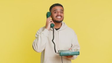 Hey sen, beni ara. Hintli genç adam 80 'lerin sabit telefon hattından konuşuyor. Reklam teklifi, online alışveriş, yardım hattı. Sarı arka planda izole edilmiş Arap adam.