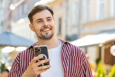 Mutlu, esmer, sakallı, akıllı telefon kullanan internet sosyal medya uygulamasına girip mesaj yazan açık havada sohbet eden bir adam. Şehir caddesinde yürüyen bir turist. Yaşam Tarzları