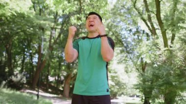 Atletik formda koşucu başarıyı kutluyor. Çığlık atıyor. Zafer maratonunu kutluyor. Sunny Park 'ta kardiyo eğitimi. Asyalı genç adam sağlıklı yaşam tarzını seviyor. Aktif sporcu motivasyonu