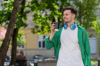 Mutlu Kafkasyalı yetişkin adam sabah kahvesinin tadını çıkarıyor sıcak içecek ve gülümsüyor. Dinleniyorum, ara veriyorum. Şehir merkezindeki caddede dikilen genç adam kahve içiyor. Dışarıdaki kasaba yaşam tarzları.