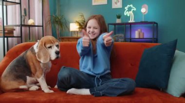 Gibi. Mutlu, beyaz bir kız çocuğu kameraya bakıp olumlu bir işaret veriyor. İyi bir şey. Oturma odasında tatlı bir av köpeği olan genç kız kanepede oturuyor.