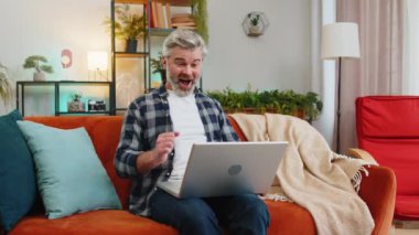 Dizüstü bilgisayarı kullanan başarılı bir kıdemli adam inanılmaz teklifleri okuyor, zafer anını kutluyor, yumruklarını sıkmaktan zevk alıyor. Sakallı beyaz adam evdeki kanepede netbook üzerinde çalışıyor..