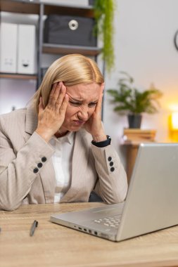 Diz üstü bilgisayara bakan sinirli olgun bir kadın, kötü düşük internet bağlantısından rahatsız olmuş, ofis evinde uzaktan çalışan stresli bayan zor iş ya da sistem çökmesi yüzünden mutsuz..