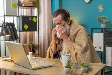 Soğuk algınlığı ya da alerjiden muzdarip hasta bir adam ev bilgisayarında çalışıyor. Yönetici serbest çalışan büyükbaba battaniyeye sarılmış hapşırık mendile sümük, peçeteye sümük, masa başında ilaç alıyor.