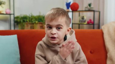 Sessiz olun lütfen. Ergen çocuk işaret parmağını dudaklarına bastırıyor. Sessiz ol işareti yapıyor. Dedikodu sırrını kimseye söyleme. Genç erkek küçük çocuk evde oturma odasında kanepede oturuyor.