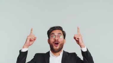 Hintli işadamı başparmaklarını havaya kaldırarak boş bir yeri işaret ediyor. Ticari metin fotokopi alanı reklamı için reklam alanı. Gri arka planda izole adam
