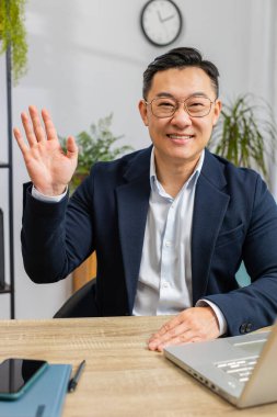 Hoş geldiniz. Bilgisayarda çalışan Asyalı iş adamı kameraya gülümseyen, el sallayan, selam veren, selamlayan ya da hoşça kal diyen ev işyerinde misafirperver bir ifadeyle karşılayan. Dikey