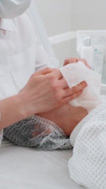 Kozmetik uzmanı kadınları güzellik kliniğinde pamuk pedlerle, yakın plan portrelerle siliyor. Güzellik uzmanının kozmetik derisi temizleme prosedürü. Güzellik endüstrisi konsepti. Dikey