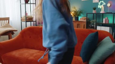 Dertsiz, genç, beyaz bir kız evinde, kafasının arkasında kanepede rahatça oturuyor. Gülümseyen, reşit olmayan bir kız çocuğu kanepede dinleniyor. Daire odasına bakıyor..