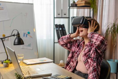 Heyecanlı iş kadını, modern ofis işyerindeki 3D 360 video simülasyonu için sanal gerçeklik fütüristik VR uygulama cihazını kullanıyor. Heyecanlı serbest çalışan kadın. Uzak uzaktaki çevrimiçi çalışma