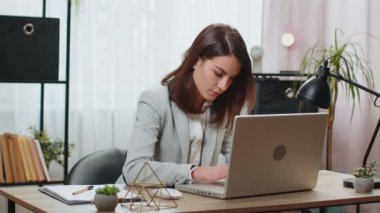 Takım elbiseli beyaz bir iş kadını, ofis masasında yaratıcı bir proje için önemli bir karar düşünüyor. Kendine güvenen serbest çalışan kız dizüstü bilgisayardaki analitik raporlara bakmakla meşgul..