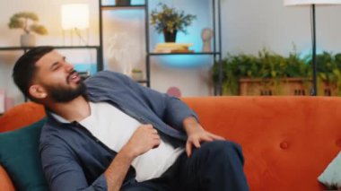 Sıkıcı genç Hintli adam, günlük kıyafetleriyle uyuyor, esniyor, evdeki kanepede huzurlu bir hafta sonu rahatlığının tadını çıkarıyor. İspanyol adam ellerini uzatıyor, dinleniyor, uyuyor, enerji eksikliği çekiyor..