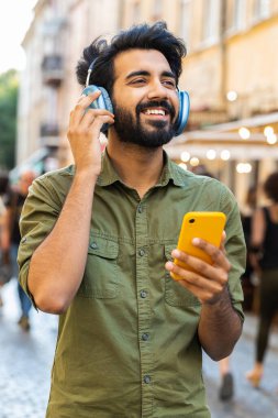 Kablosuz kulaklıklı mutlu, gevşemiş Hintli Arap adam dışarıda dans eden enerjik disko rock 'n roll müziği dinliyor. Şehirdeki Sunshine Sokağı 'nda duran adam. Dikey