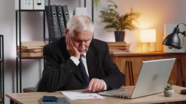 Takım elbiseli Kafkasyalı serbest muhasebeci mali grafik belgeleriyle çalışıyor, çizelgeler için vergileri hesaplıyor ve ofis masasında raporlar hazırlıyor. Dedem dizüstü bilgisayarda çalışıyor, harcama bütçesi planlıyor..