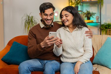 Kanepede oturan ve akıllı telefonları çalan çok ırklı genç bir çift. Mutlu Hintli erkek ve kadın birlikte tartışarak zaman geçirir, dinlenir ve cep telefonuyla iletişim kurar.