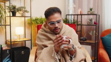 Ekoseli hasta Hintli adam kanepede soğuktan titreyerek oturur ısınmamış bir dairede sıcak çay içerken borcunu ısıtmaz. Sağlıksız Arap adam koltuğa oturur ve kendini rahatsız hisseder.