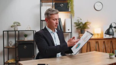 Merkez büro masasında çalışan beyaz iş adamının POV 'u grafik analizleri gösteriyor ve çalışanla çevrimiçi iletişim videosu hakkında konuşuyor. Freelancer destek servisi kameraya bakıyor..