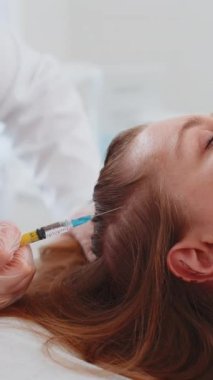 Alopecia. Kadın saç dökülmesi tedavisi. Trikoloğun kozmetolojisti kafa derisi dermapen fraksiyonel mikronedle kliniği mezoterapisine bir şırıngadan vitamin serumu enjekte ediyor.