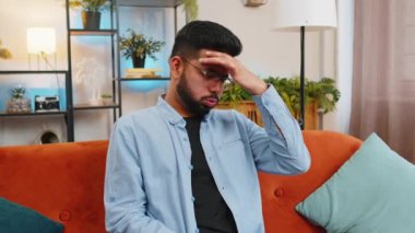 Hasta Hintli adam baş ağrısı problemini tedavi etmek için tapınakları ovuyor, tansiyon, migren, stres, ekşitme, evde yüksek tansiyon. Arap adam evdeki kanepede gözlük çıkartıyor..