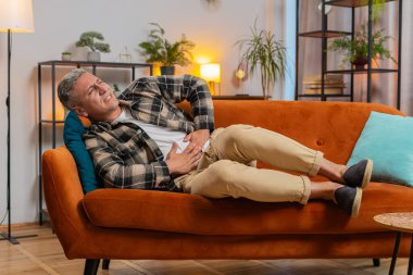 Genç, beyaz bir adam kanepeye uzanmış karın ağrısı ve mide iltihabı şikayeti yaşıyor. Semptom zehirlenmesi geçiren bir adam ishal hazımsızlık peptik ülser pankreatiti geçiriyor..