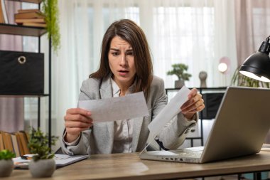 Beyaz iş kadını zarfı açıp mektupta kötü haberler okuduğu için ofis masasında oturduğu için üzülüyor. Finansal sorunlar, banka borç ödeme faturası, vergi faturası veya iflas bildirimi.