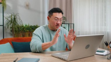 Asyalı bir adam dizüstü bilgisayar kamerasına bakıyor, arkadaşları ya da ailesi ile görüntülü bir konferans görüşmesi yapıyor, evde hoş sohbetler ediyor. Gülen, el sallayan bir adam masanın üstünde oturuyor.