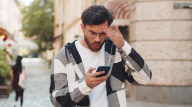 Hintli genç adam akıllı telefon daktilo kullanıyor. Ani piyango sonuçlarını kaybediyor. Kötü haber, servet kaybı, başarısızlık. Şehir caddesinde duran turist. Kasaba yaşam tarzları.