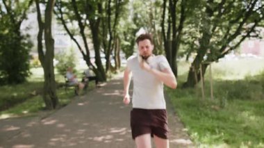 Şehir parkında koşan ve akıllı adam arayan mutlu koşucu. Heyecanlı erkek, spor takip cihazı kullanıyor ve başarıyı kutluyor. Sporcu çocuk antrenman sonuçlarından memnun..