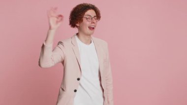 - Tamam. Kıvırcık saçlı mutlu beyaz adam kameraya onaylayıcı bir şekilde bakıyor. Pozitif geri bildirim yapıyor, iyi bir şey onaylıyor, zaferi kutluyor. Stüdyo pembe arka plandaki adam