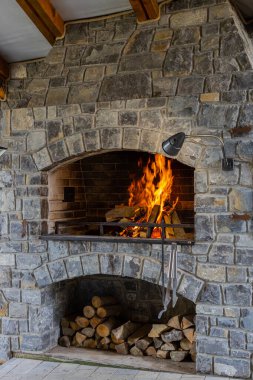 Ateşli yanan taş barbekü odunu, yemek pişirmek için açık tuğla fırın et balığı, arka bahçede diğer tabaklar. Restoran mutfağı, pizza fırını, barbekü. İç yapı. Dikey