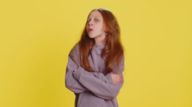 Neşeli, neşeli, genç, kızıl saçlı kız kameraya surat asıyor, şakalaşıyor, aptal suratıyla şakalaşıyor, alay ediyor, zorbalık ediyor, taciz ediyor. Sarı arka planda reşit olmayan çocuk.