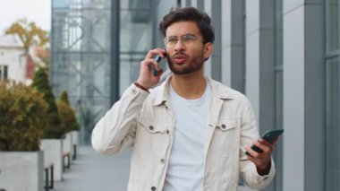 Sinirli, stresli Hintli bir adam iki cep telefonuyla bağırarak konuşuyor. Tartışıyorlar. Tartışıyorlar. Şikayet anlaşmazlığı dışarıda çözülüyor. Şehir merkezindeki Arap Hindu adam.