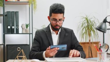 Akıllı telefon uygulamalarıyla oynayan Hintli işadamı ofis masasında oyun kazanma ya da atıcılık oyunlarını kutluyor. Profesyonel yönetici serbest çalışan adam yeni uygulamanın iyi çalışmalarını test etmekten zevk alır