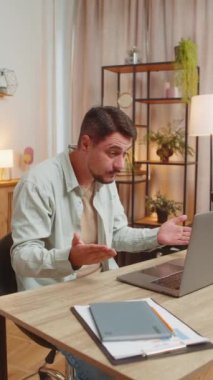 Ev ofisinin bilgisayarında çalışan serbest çalışan genç bir erkek çalışanla online iletişim videosu konuşması yapıyor, patron. Bilgisayar webcam 'ine bakan yönetici destek servisleri. Dikey.