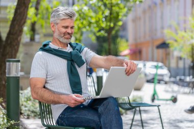 Yetişkin bir adamın portresi, açık şehir sokaklarında sandalyede oturan dizüstü bilgisayarı açıyor. Kafkas sakallı adam defter üzerinde çalışıyor, mesajlar gönderiyor, internetten alışveriş yapıyor, film izliyor. Kasaba yaşam tarzları.