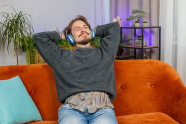 Kablosuz kulaklıklı, rahat rahat kanepede uzanan ve en sevilen disko rock n roll müziğini dinleyen neşeli, beyaz sakallı adam. İnsanlar hafta sonu aktiviteleri
