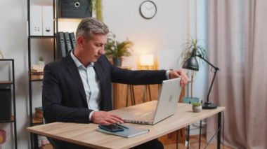Resmi takım elbiseli genç, gri saçlı işadamı dizüstü bilgisayarı açıyor mesajlar gönderiyor, filmler izliyor, online alışverişler yapıyor. Modern ofis çalışma alanında netbook kullanan beyaz bir adam..