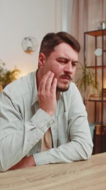 Beyaz, serbest çalışan genç bir adam ofis masasında oturmuş diş ağrısının ağıza dokunduğunu hissediyor diş hastalığından dolayı acı veren bir ifade. sakız hastalığı, diş hastalıkları. Dikey.