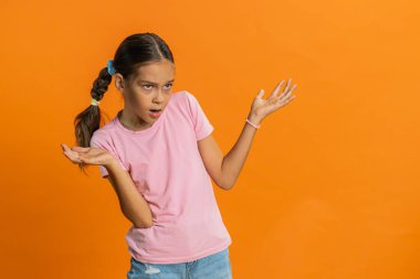 - Ne? - Neden? Öfkeli bir ifadeyle elini kaldıran genç bir kız, sorunların neden inançsızlığı gösterdiğini soruyor. Çocuk 10 yaşında, turuncu arka planda.