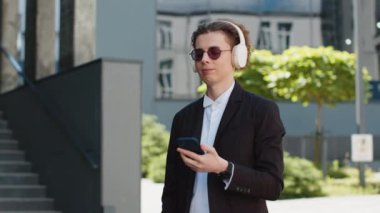 Neşeli beyaz menajer ofis binasının yanındaki sokakta yürürken kablosuz kulaklıkla müzik dinliyor. Gülümseyen adam cep telefonunun çalma listesini açar ve şarkının tadını çıkarır..