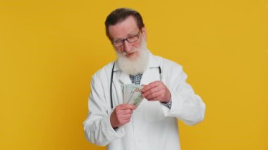 Zengin, mutlu, kıdemli doktor kardiyolog hayranı, başarılı iş kariyeri, büyük gelir kaynağı gibi banknotlar savuruyor. Eczacı dedesi sarı arka planda izole edilmiş.