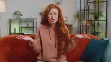 Avuç içi. Yazıklar olsun sana. Kızıl saçlı üzgün bir kadın saygısız bir jest yapıyor. Başarısız olmaktan sıkılmış olması kötü haber doğuruyor. Oturma odasında kanepede oturan kızın portresi. Yaşam Tarzları.