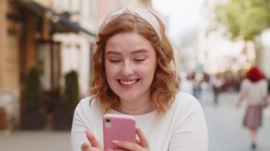 Aman Tanrım. Vay canına. Heyecanlı, mutlu, neşeli, uzun elbiseli genç kadın akıllı telefon kullanıyor, kutlama yapıyor, dışarıda iyi haberler kazanıyor. Şehir caddesinde cep telefonlu bir kız yürüyor..