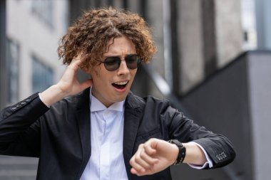 Kafkasyalı genç işadamı kol saatine bakıyor. Şok gecikmesi daha hızlı gidiyor. İşvereni binanın yakınındaki açık havada geziyor. Takım elbiseli, kıvırcık saçlı yakışıklı adam..