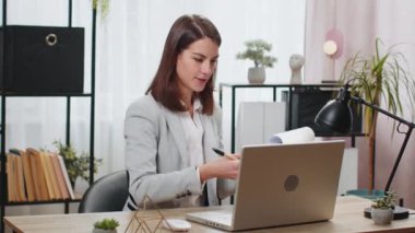 Ofis masasında çalışan genç bir iş kadını çalışanlarıyla online haberleşme videosu hakkında konuşuyor, patron grafiksel analiz gösteriyor. Kafkas kız destek hizmetleri bilgisayarın webcam 'ine bakıyor